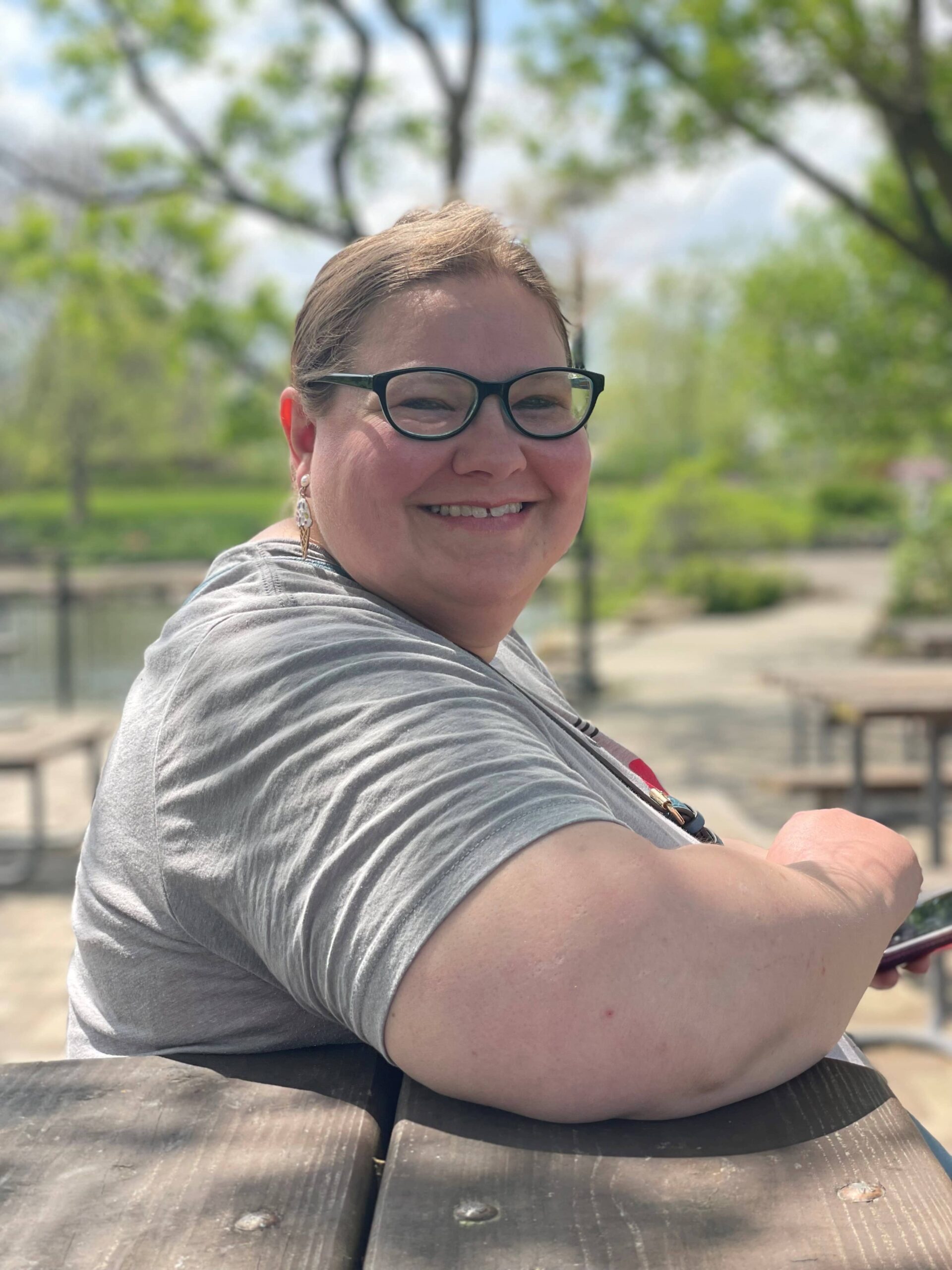 A young woman sitting on a bench outside smiling