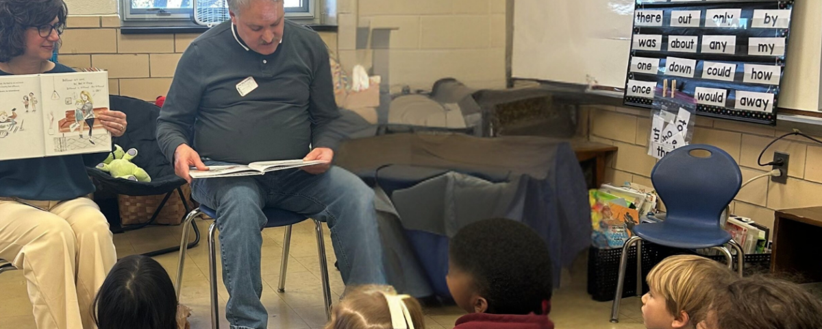 picture of man and woman reading to elementary age children