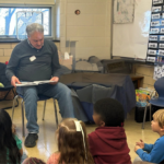 picture of man and woman reading to elementary age children