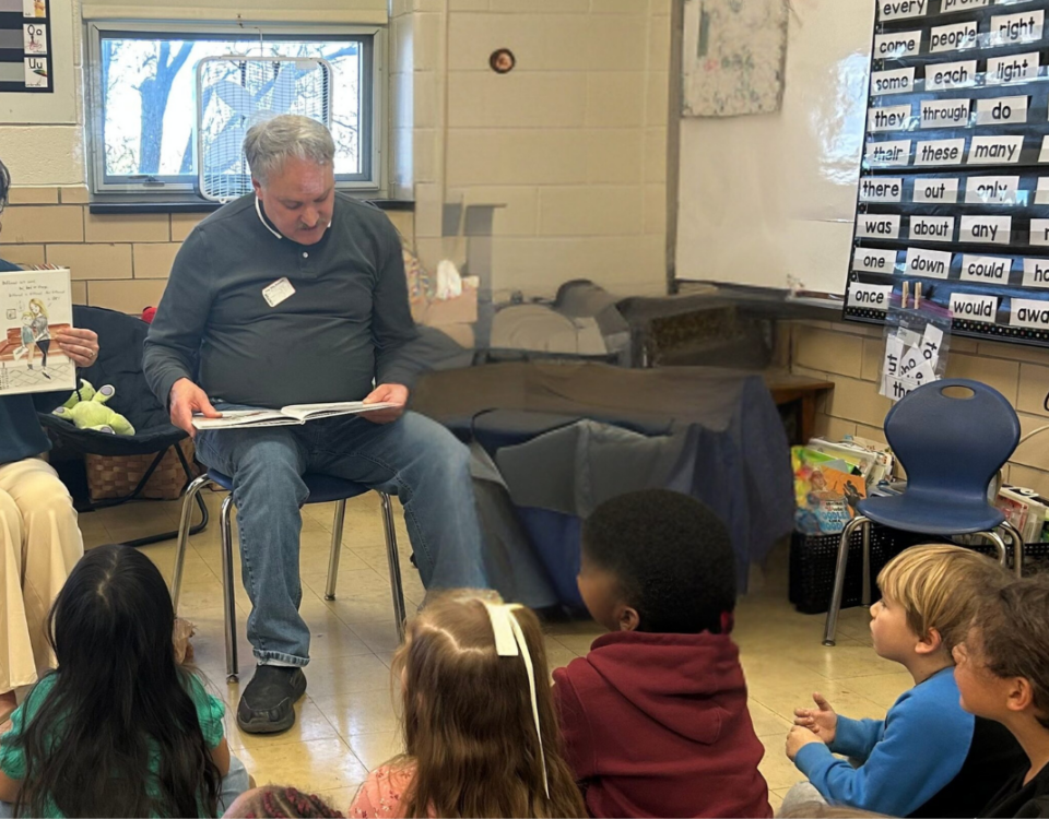 picture of man and woman reading to elementary age children
